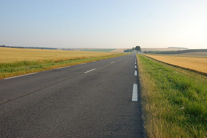 A long road with grass on the side of the road