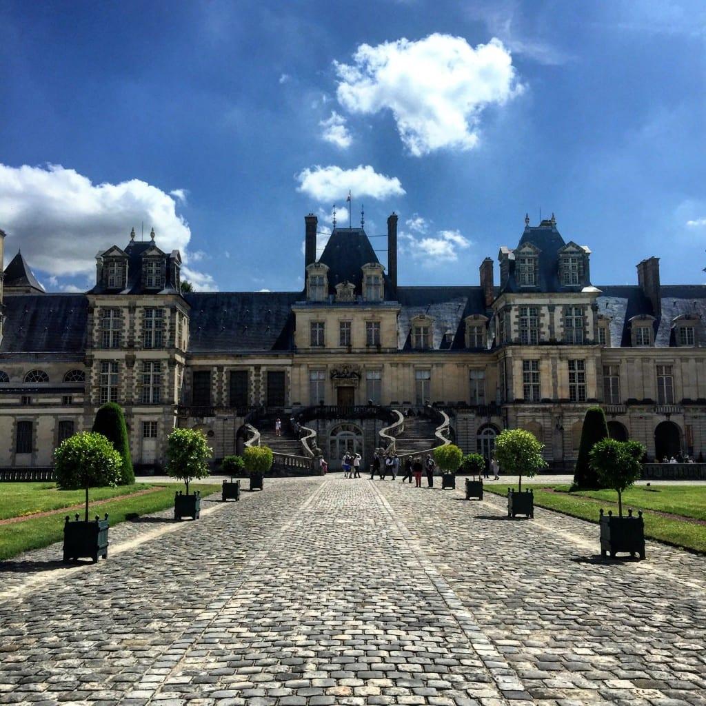 A castle on a cloudy day with Palace of Fontainebleau in the background