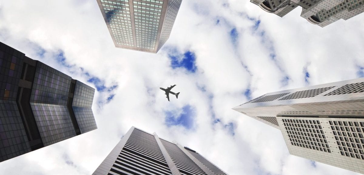 plane flying between buildings