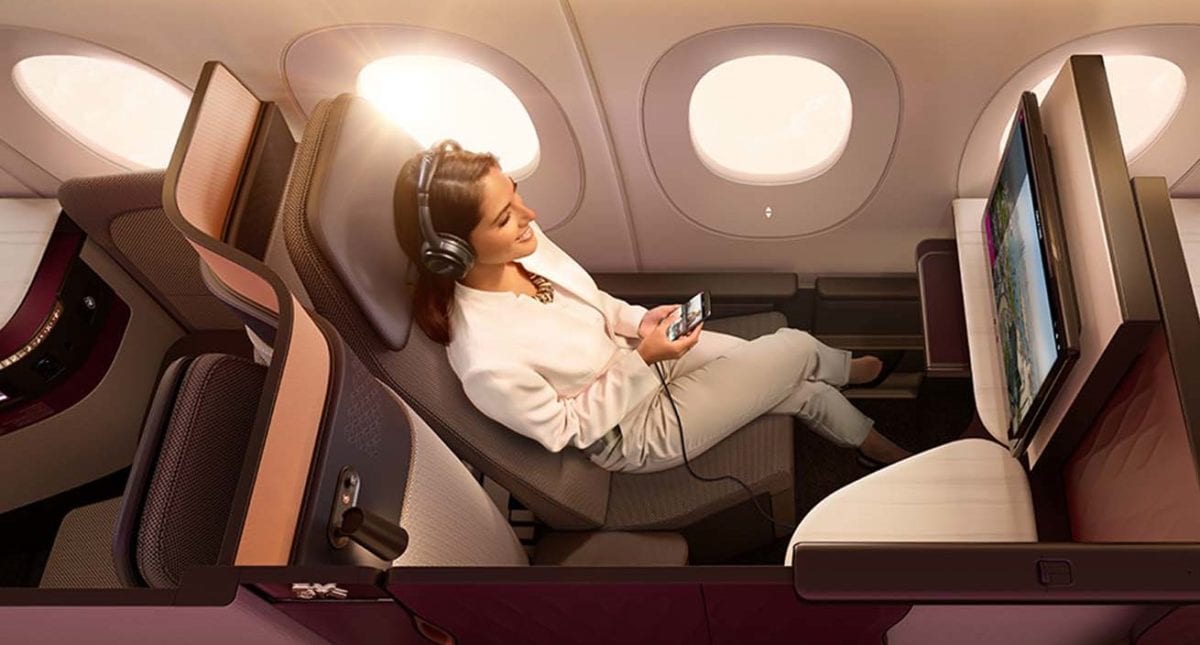 A woman sitting in a Qatar Airways qsuites seat