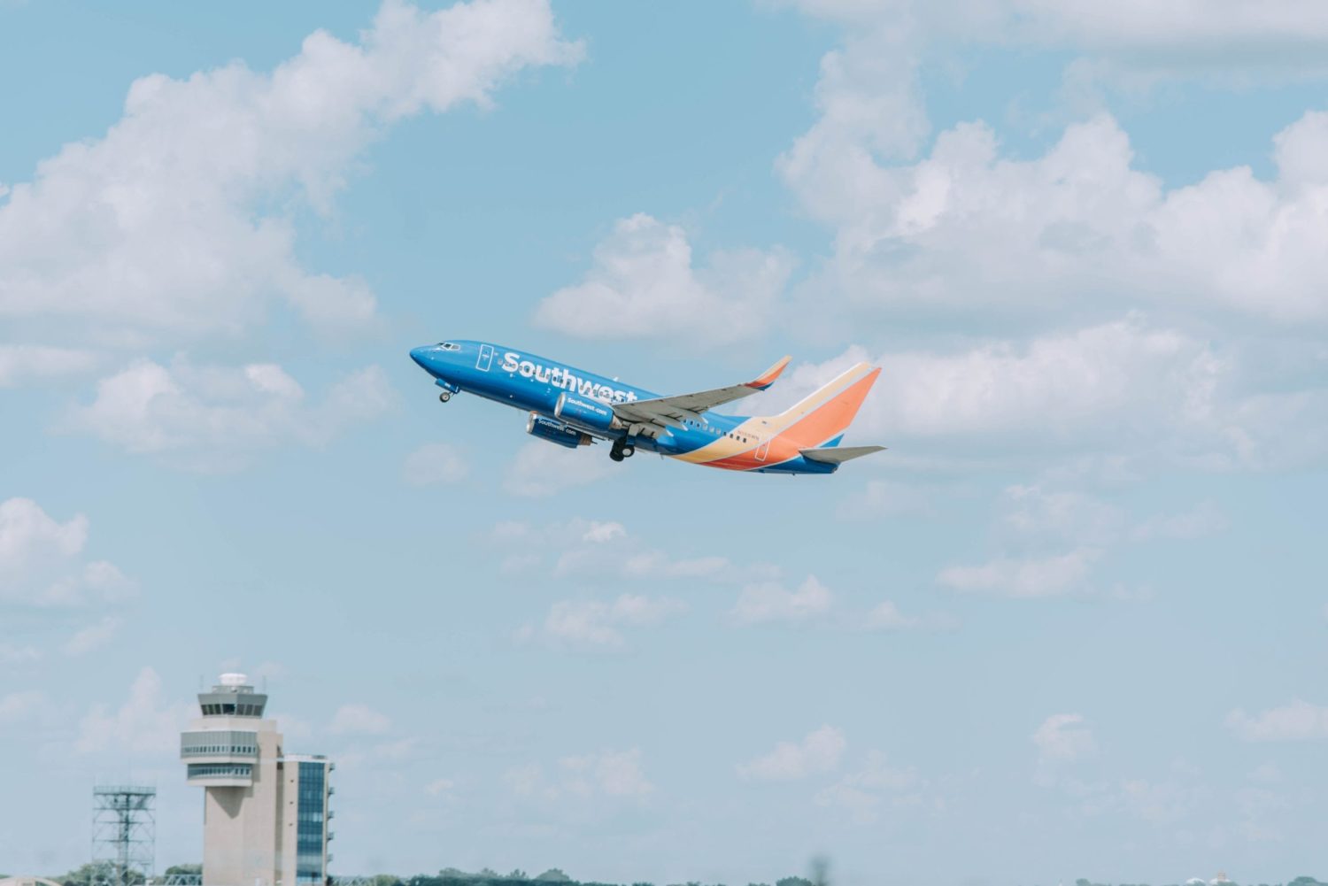 A large southwest passenger jet flying through a cloudy blue sky