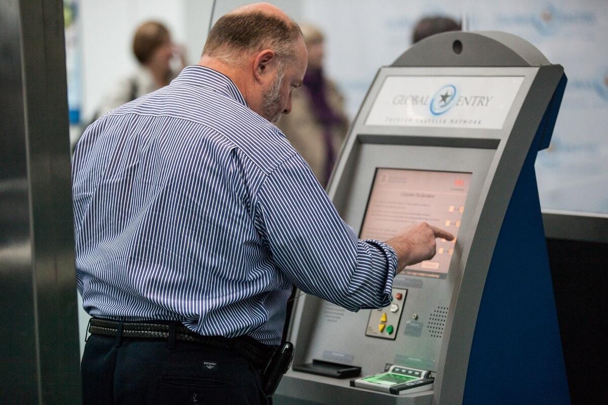 A man standing in front of a Global Entry kiosk