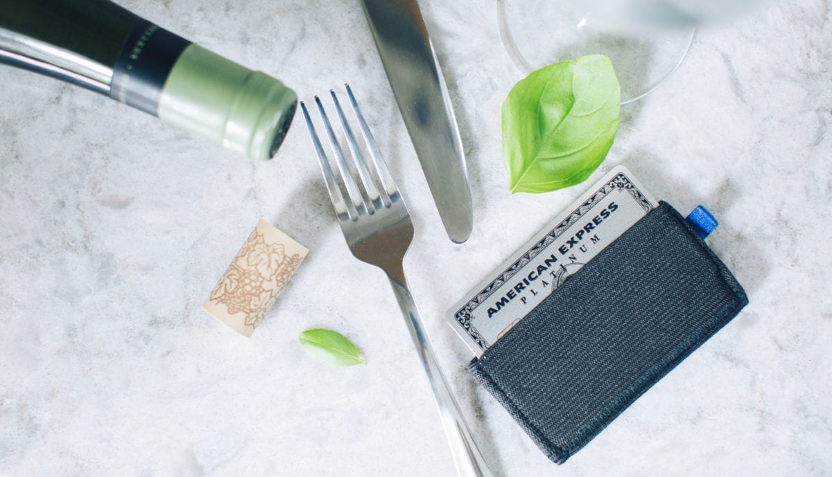 an Amex Platinum Card in a wallet on a table top with a fork and knife