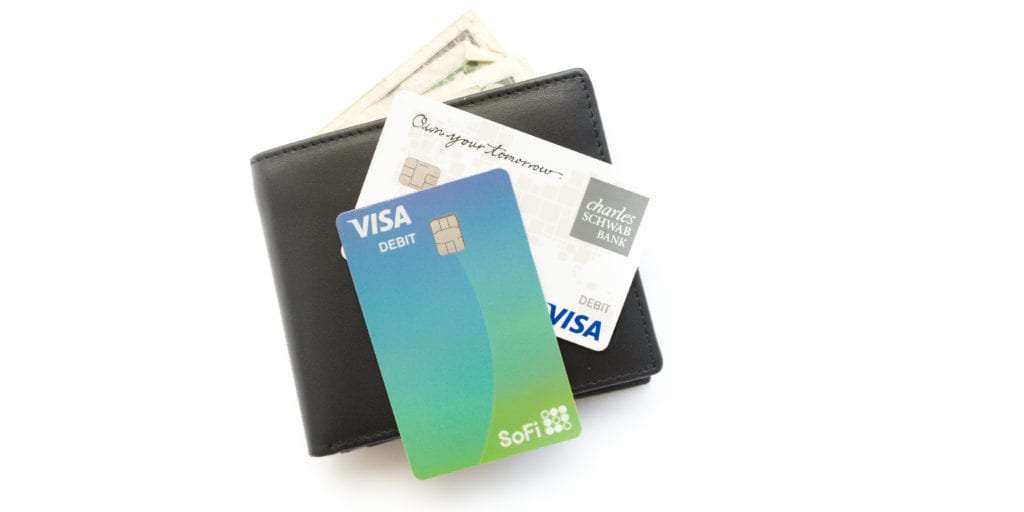 sofi money and charles schwab debit card on top of a wallet