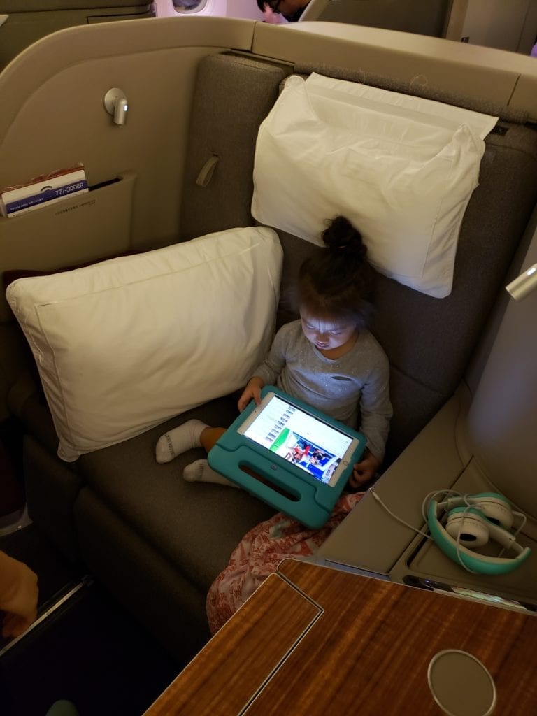 A child sitting on a plane with a laptop on a bed