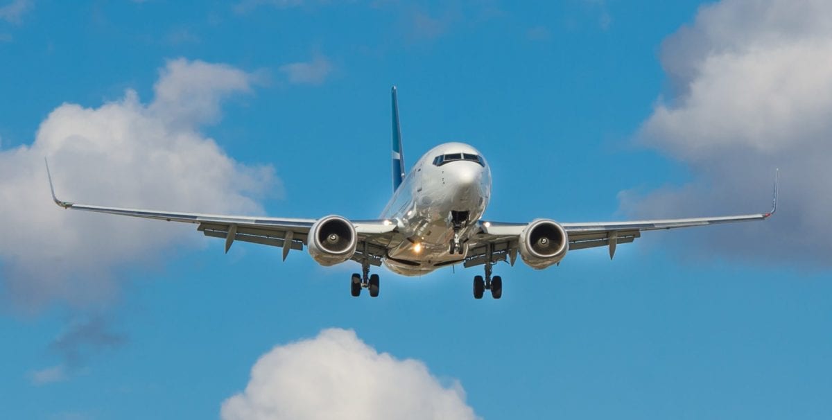 A large passenger jet flying through a cloudy blue sky