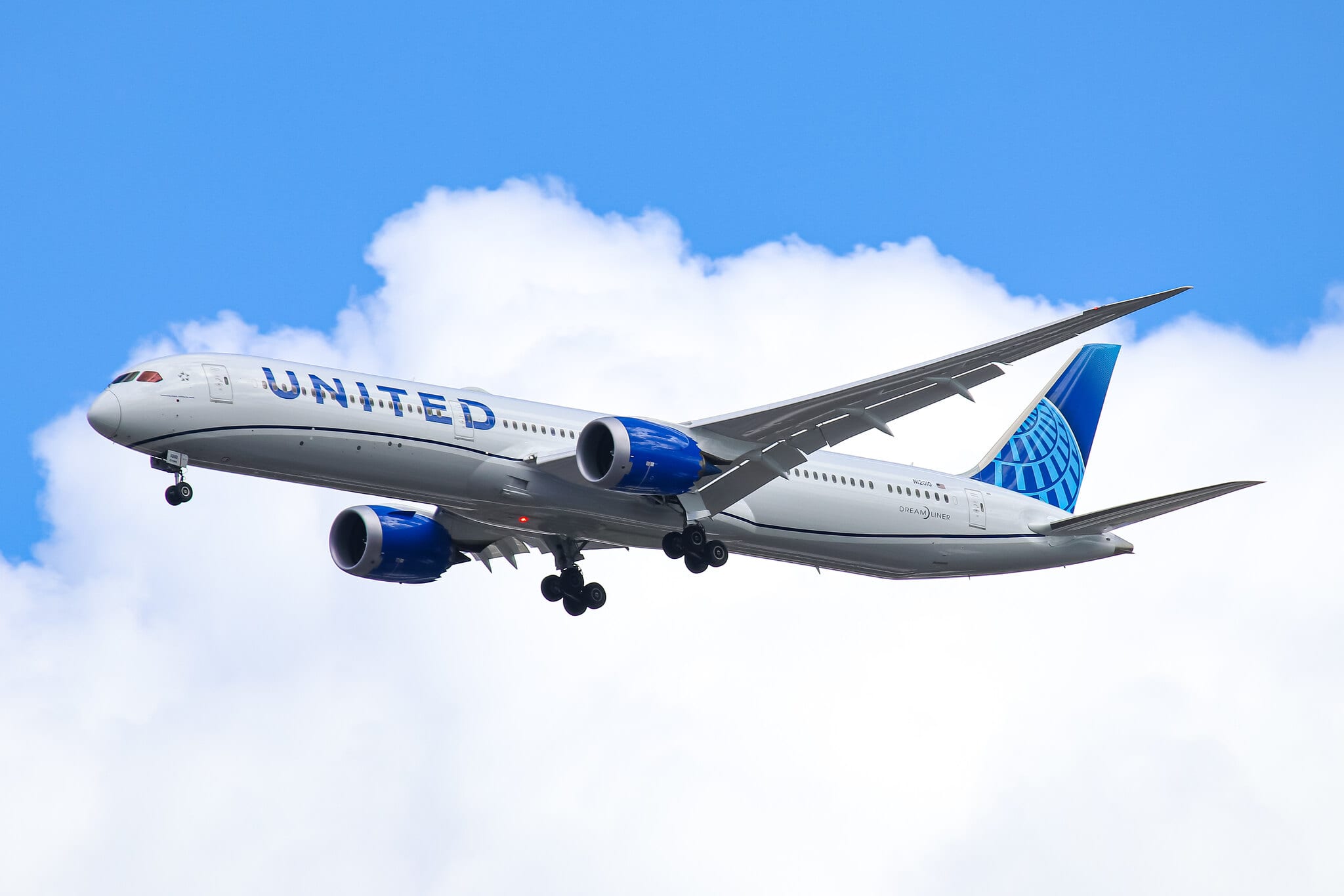 A large passenger jet flying through a cloudy blue sky