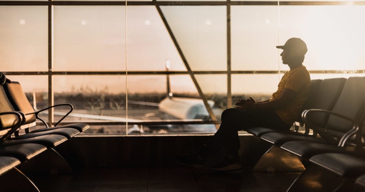 person sitting at gate in airport during sunset