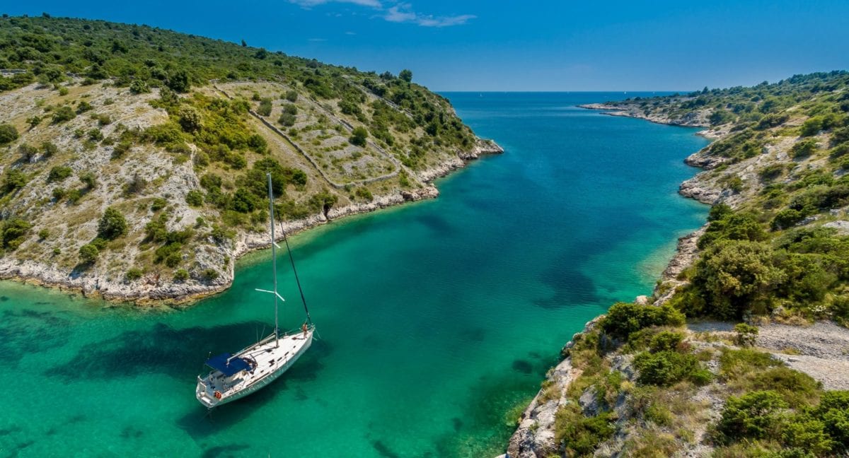 A sailboat anchored in a bay's crystal-clear blue water in Croatia