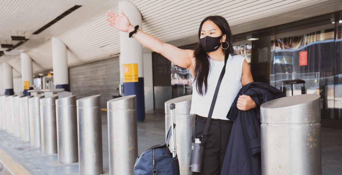 A person with a mask standing in front of an airport
