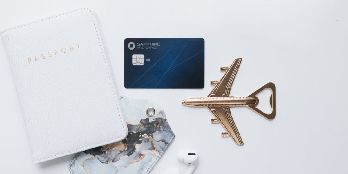 Card laying on-top of table-top with airplane keychain, airpod, and passport cover
