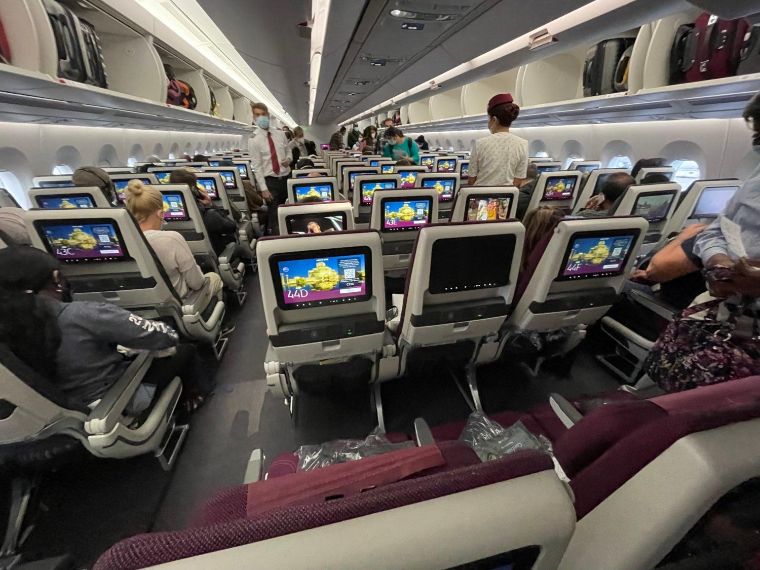 several rows of economy seats with a flight attendant