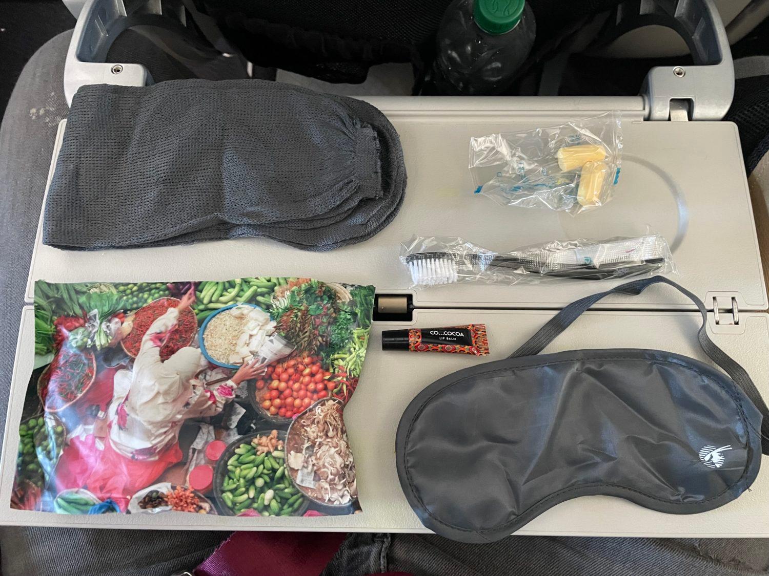 an eyemask, socks, toothbrush, and other amenities on a plane tray table