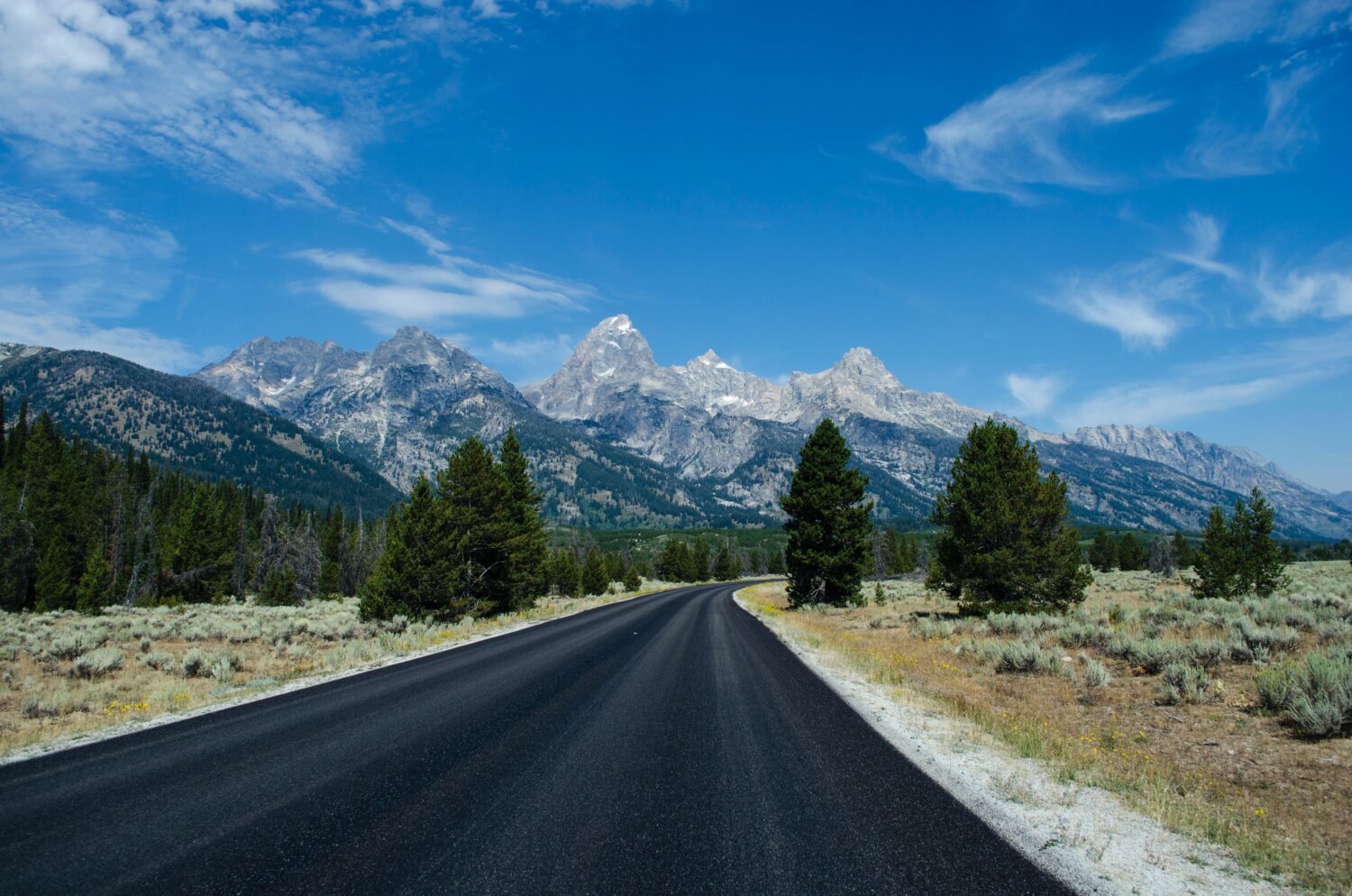 A scenic road leading to the majestic Grand Teton Mountains
