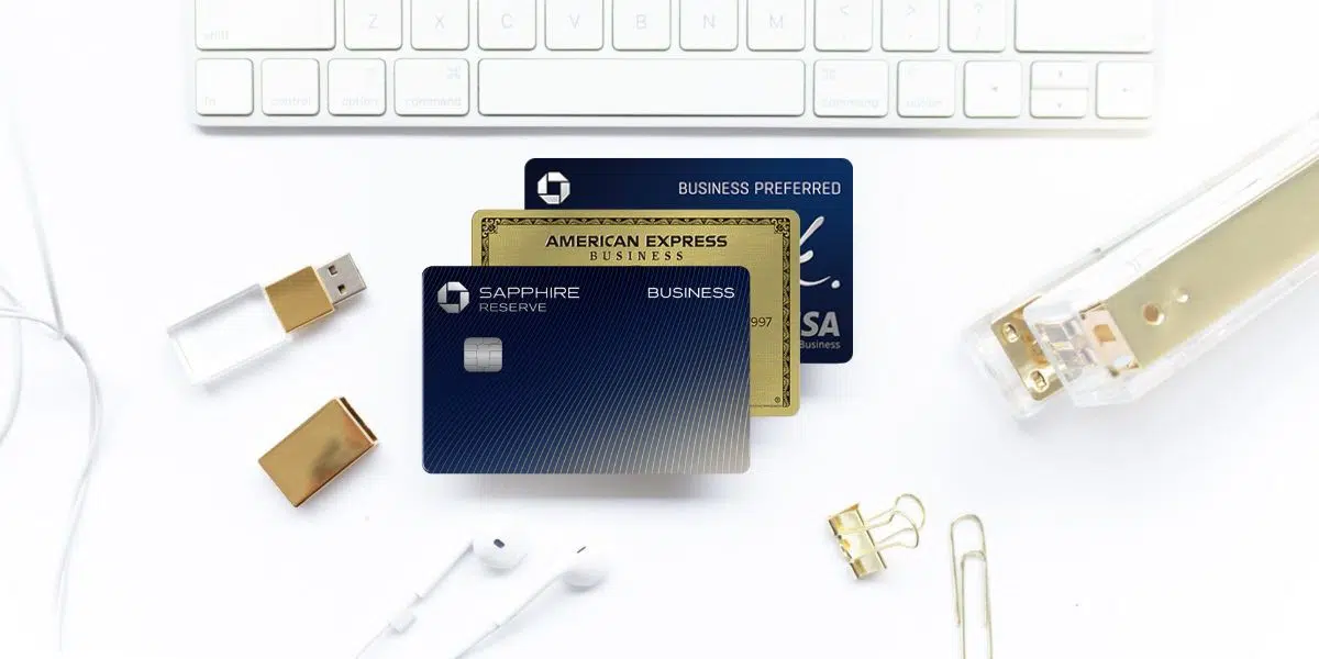 Sapphire Reserve for Business, Amex Business Gold, and Ink Preferred Cards with a keyboard, stapler, USB drive, headphones, and paper clip, on a white background.