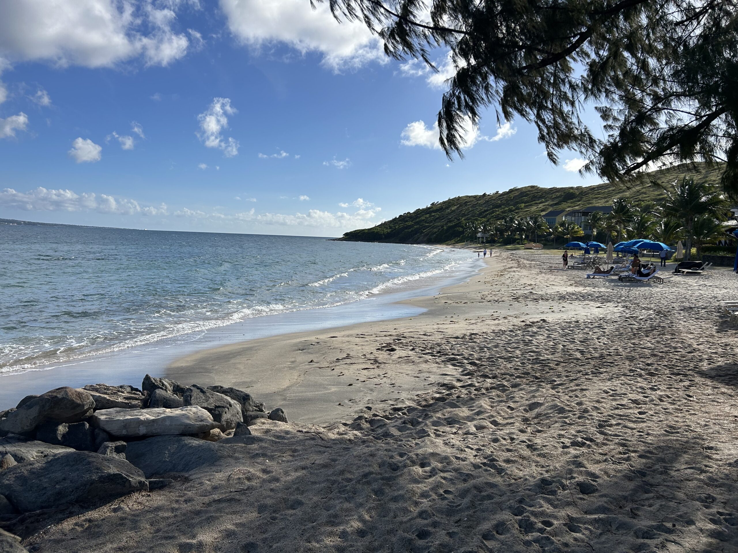 the ocean and beach with a few beach chairs and umbrellas in the distance. 