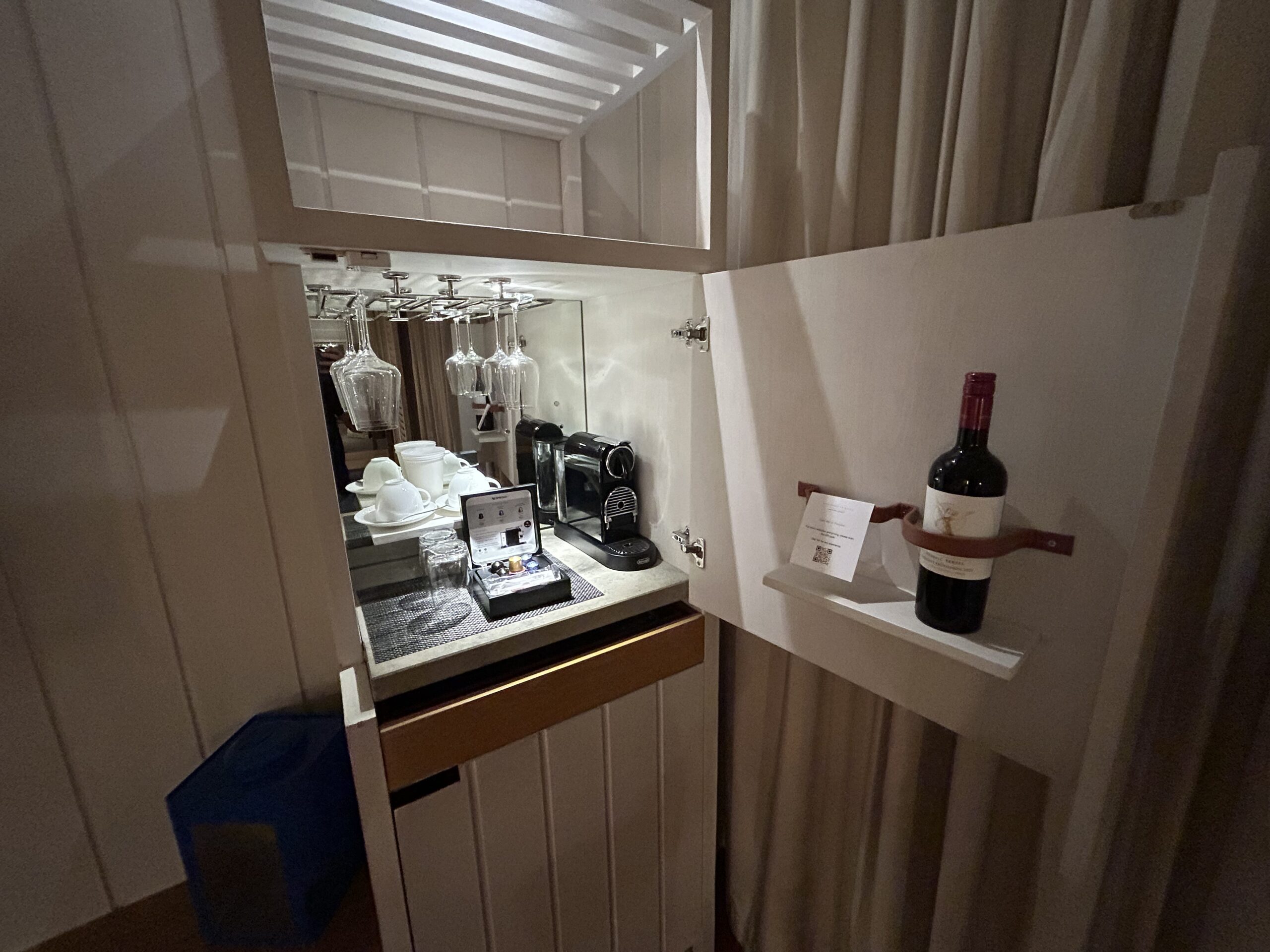 mini bar with a wine bottle holder in the door, wine glasses, and a nespresso machine