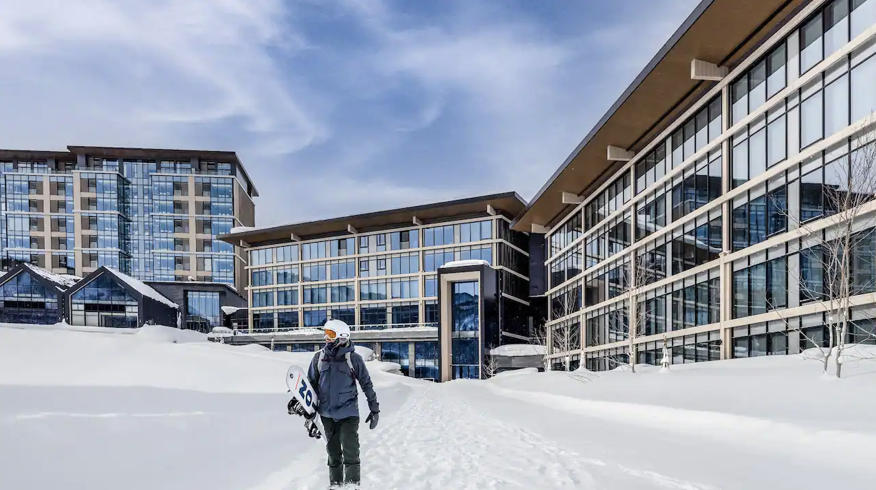 Park Hyatt Niseko Hanazono exterior property shot with snowboarder walking