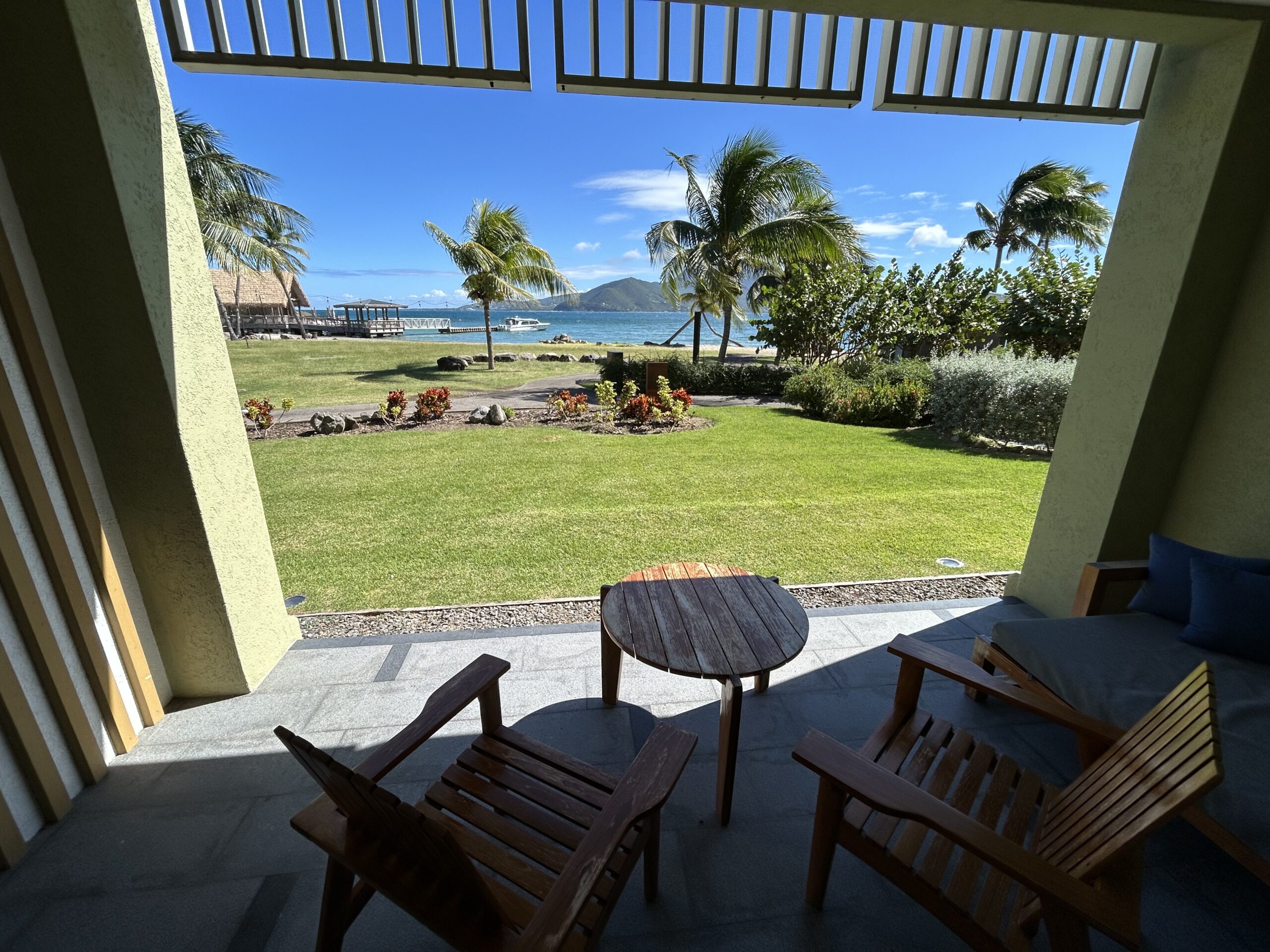 View of Nevis and the ocean from a Park Hyatt room. The patio has two wooden chairs and a small wooden table.