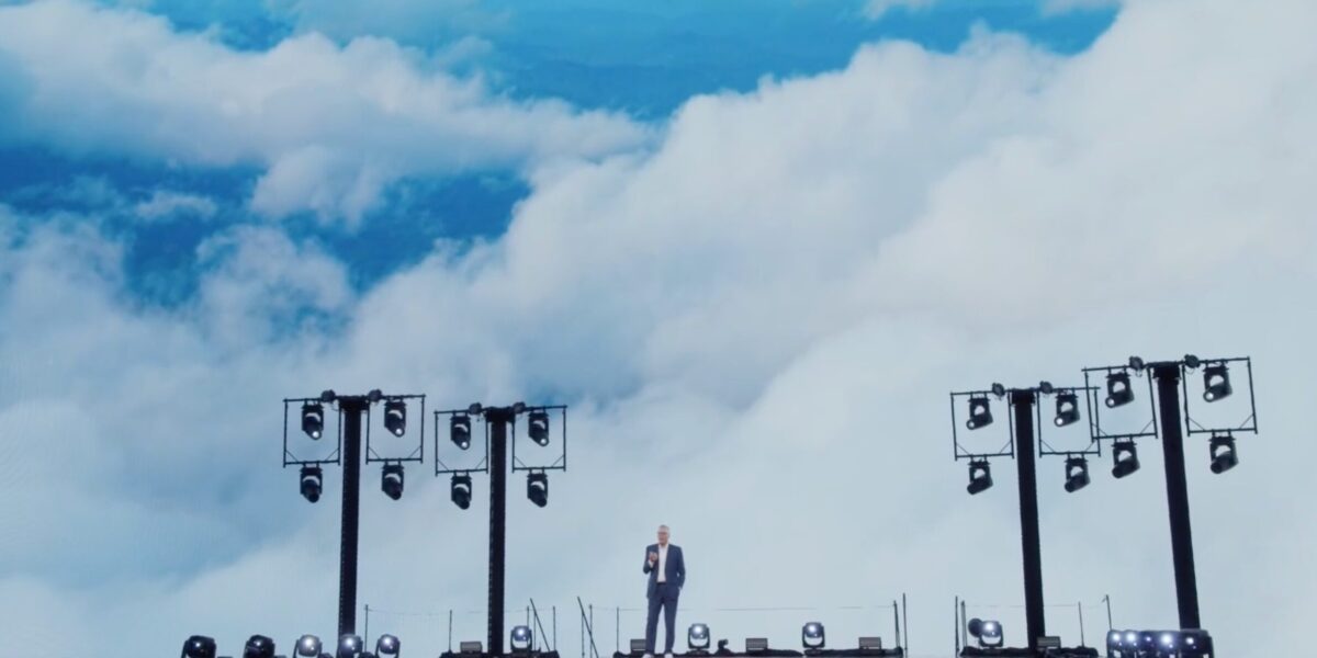 a man on a large stage with clouds in the background