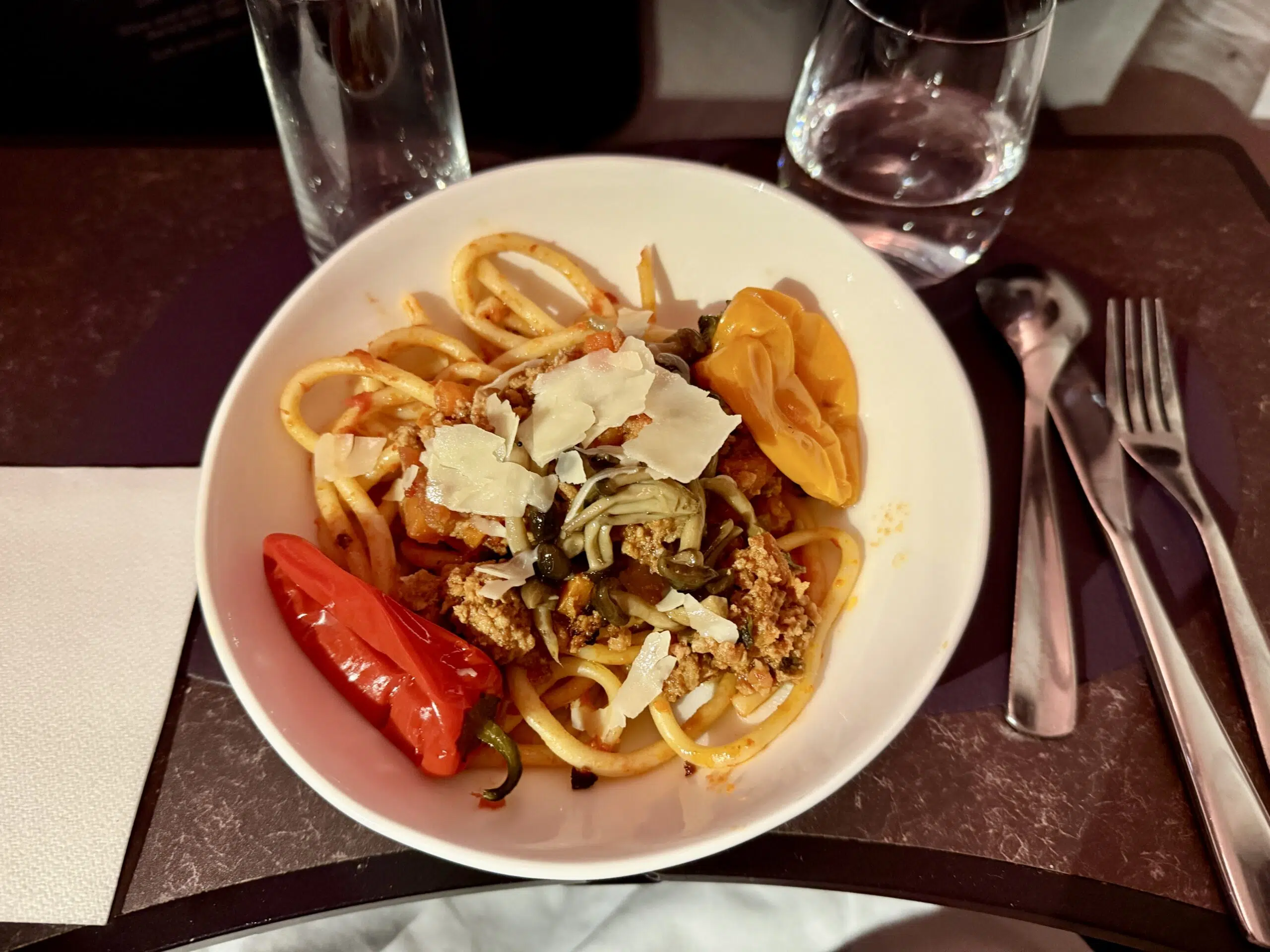 bowl of pasta topped with parmesan cheese shavings on a plane