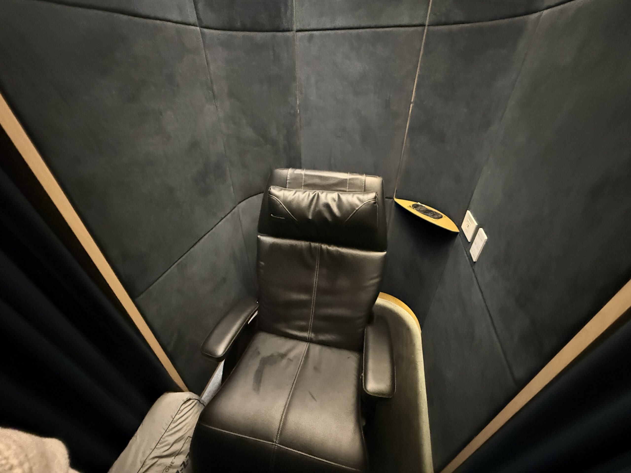 black recliner chair inside a black-walled pod