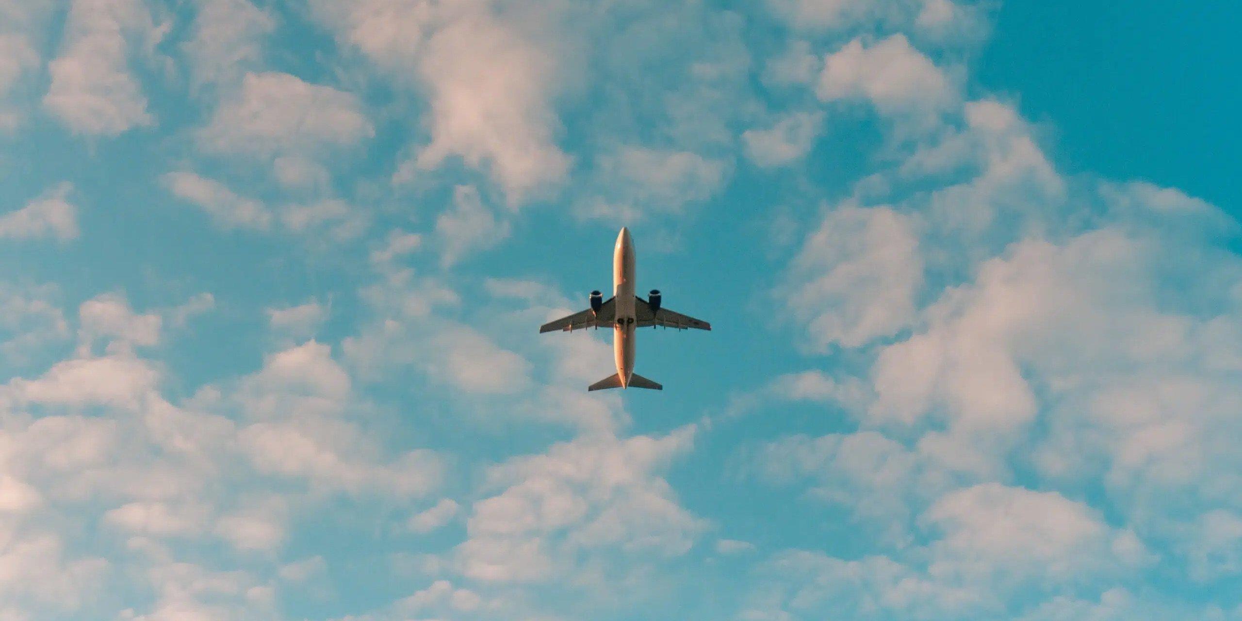 Airplane flying through the sky with light clouds