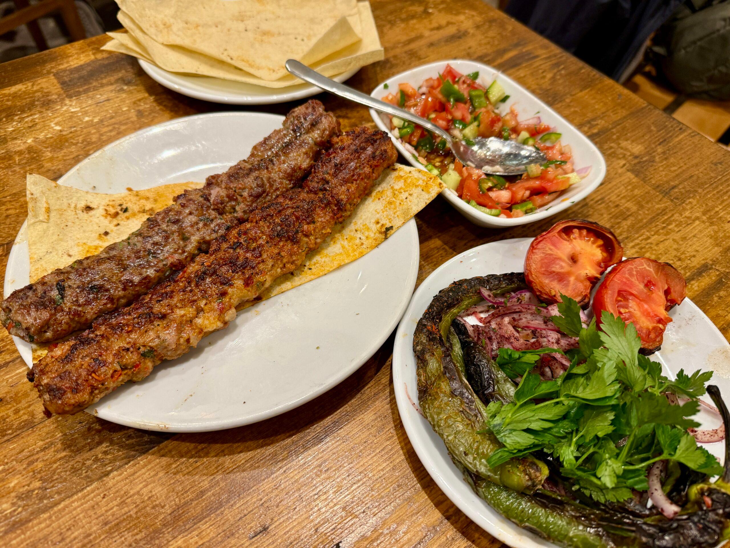 adana kebap with grilled vegetables and lavash bread on plates