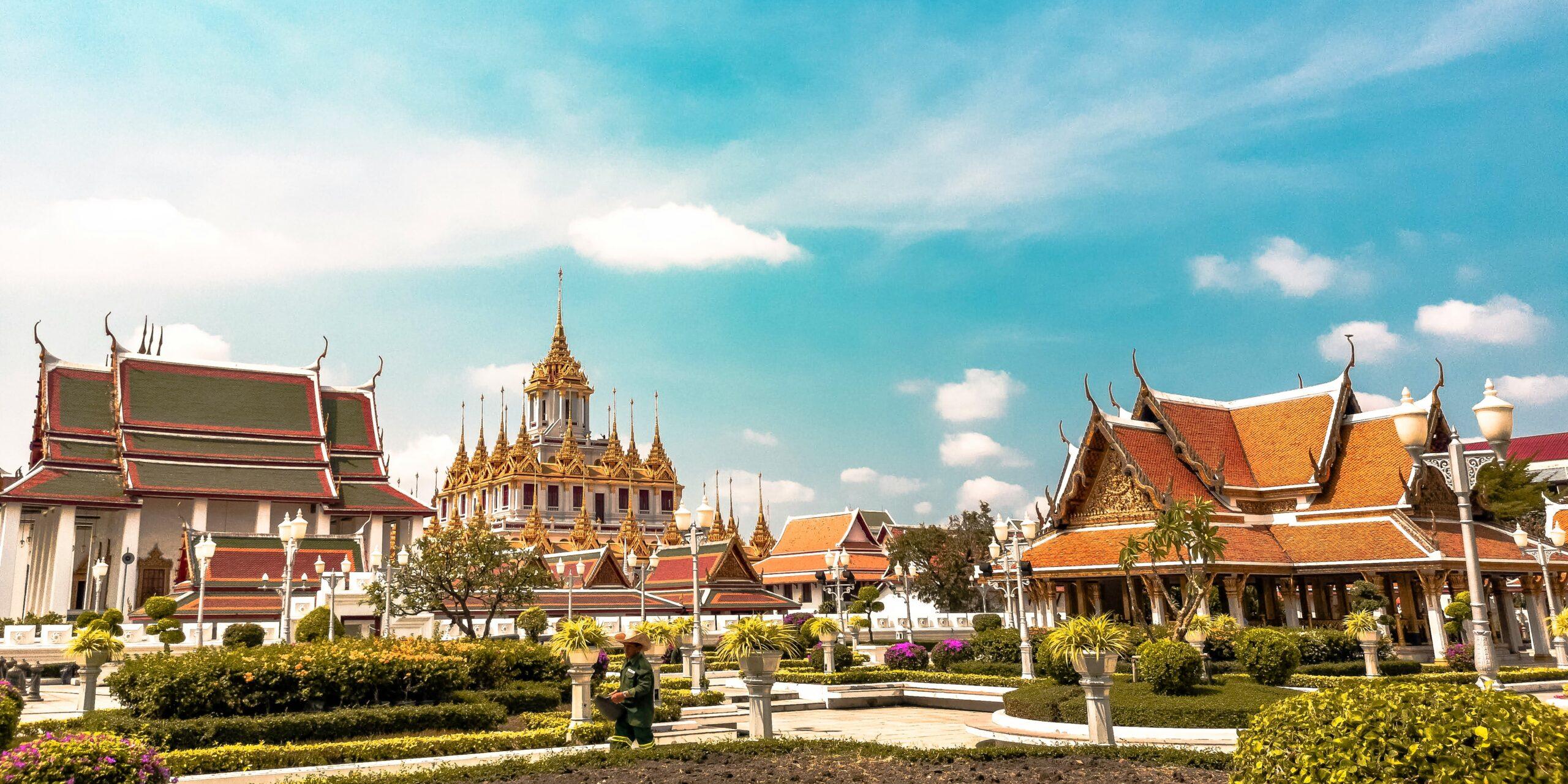 colorful temples in bangkok thailand with green shrubbery and a blue sky