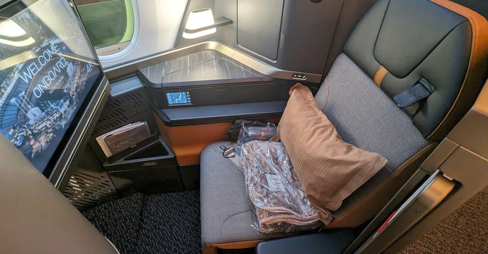 Starlux business class seat accented in orange and granite. 