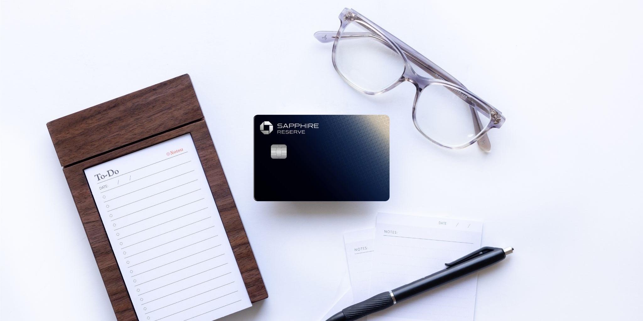 Chase Sapphire Reserve credit card with notepad, pen, and glasses.