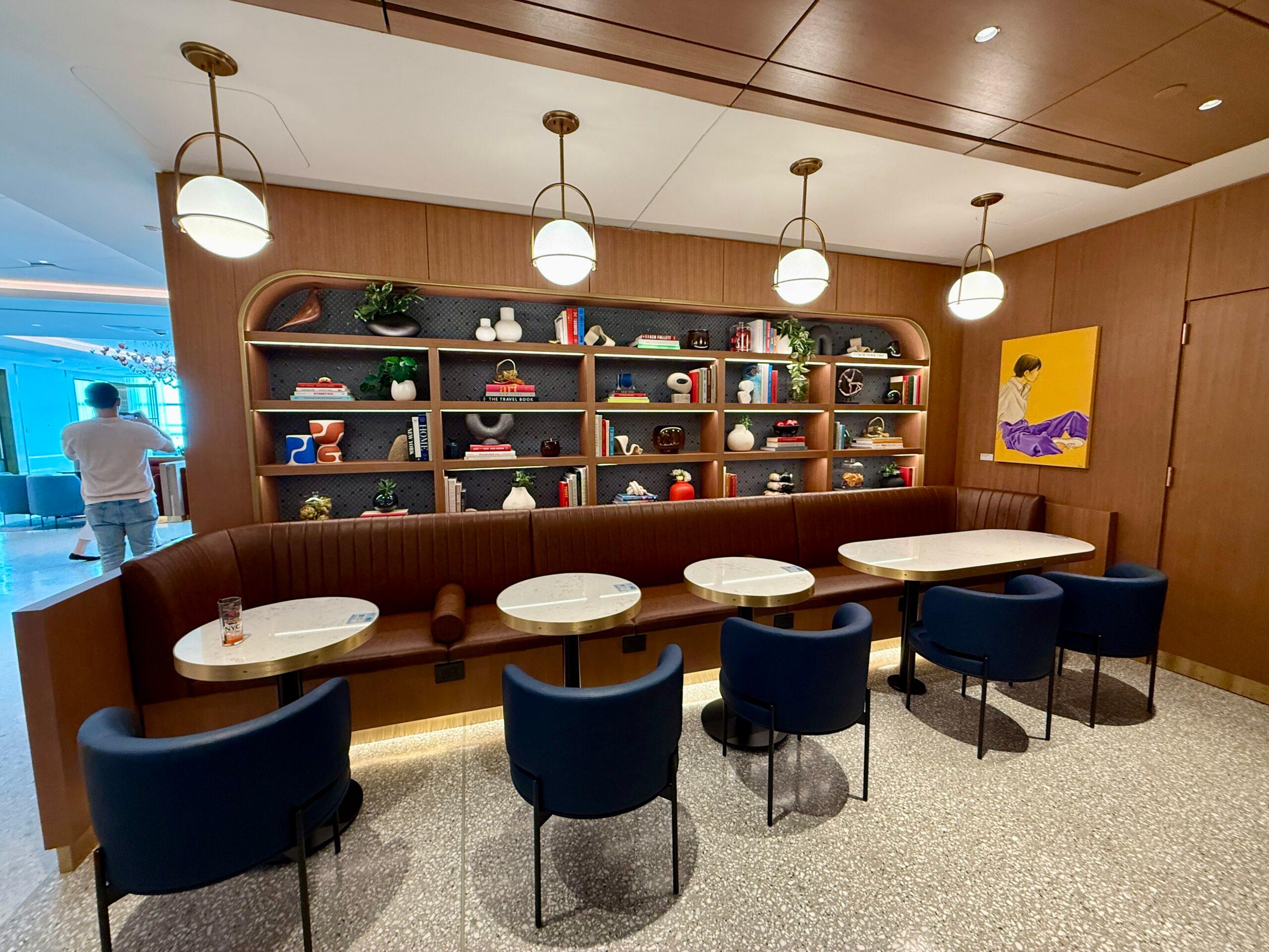 blue chairs at small circular tables in front of a long leather bench