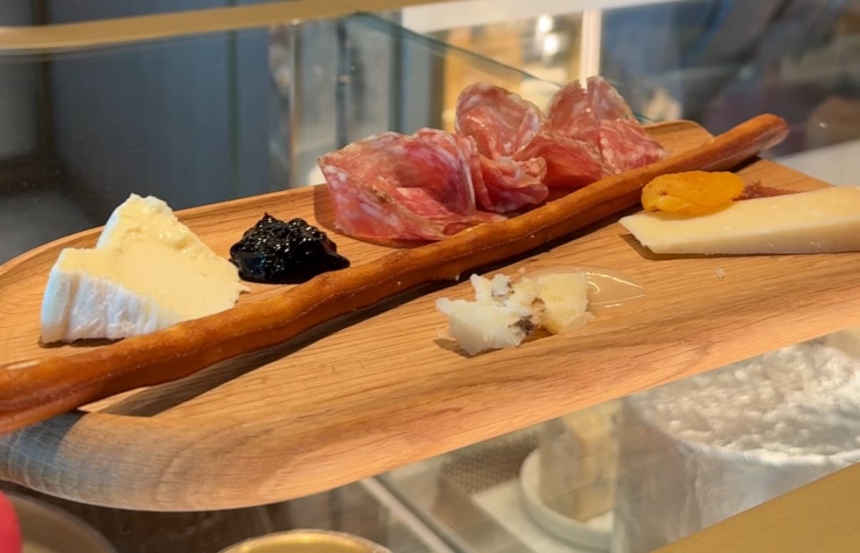 wooden board with cheese, breadstick, meats, and jams