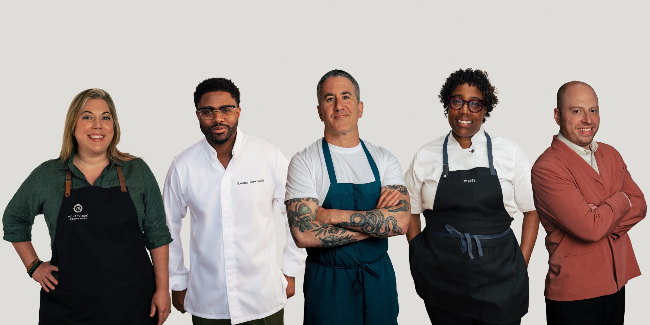 Five chefs standing in a line with a white background. 