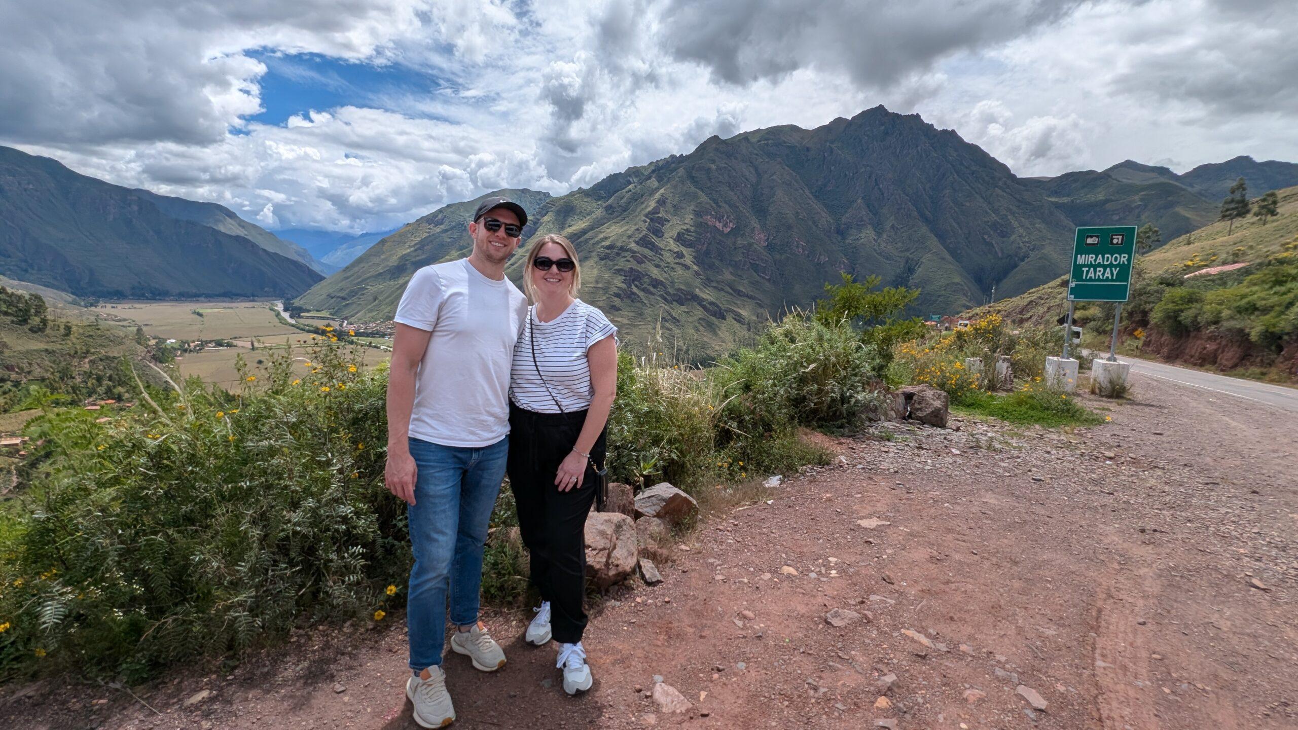 A man and woman standing at a scenic overlook entering the Sacred Valley, Peru. 