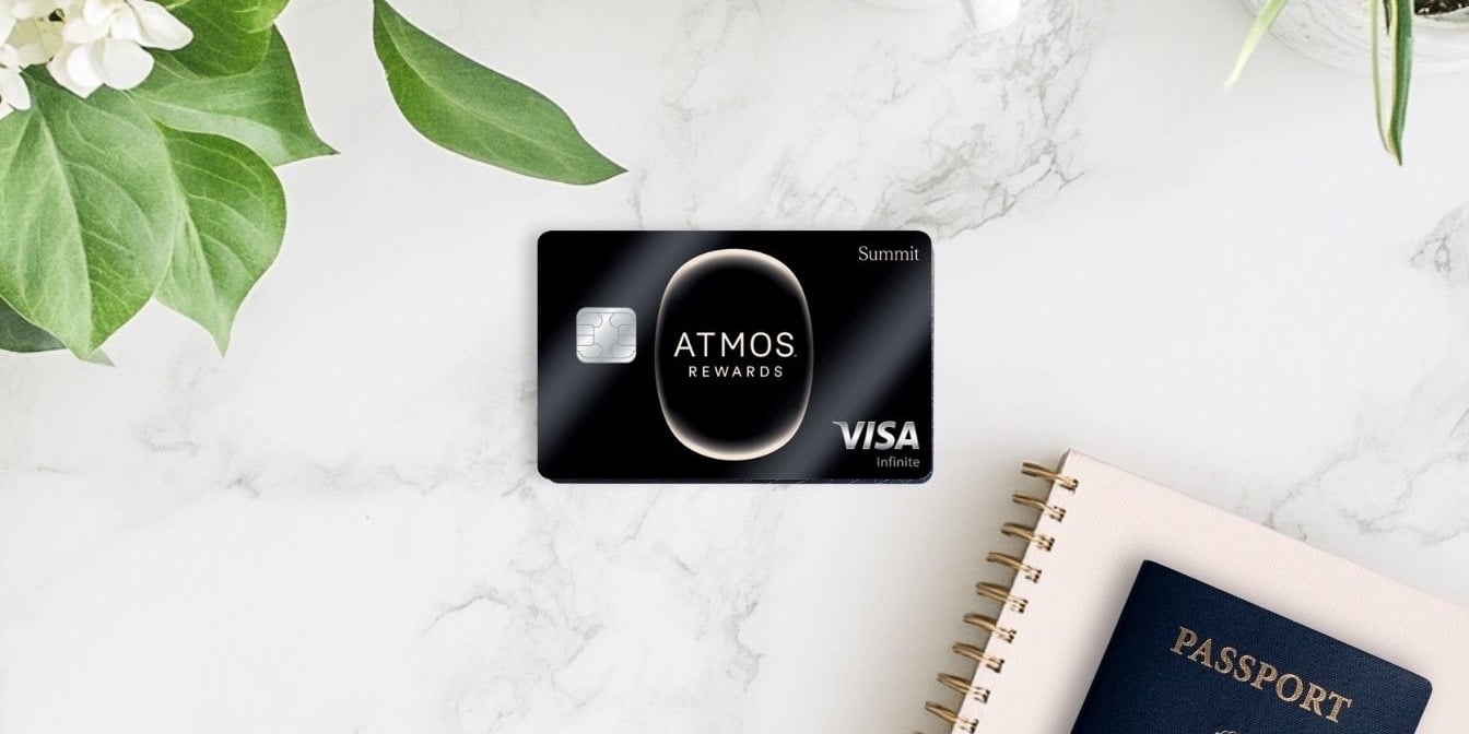 Atmos Rewards Summit Card on a marble countertop with a notebook, passport, and plant surrounding it.