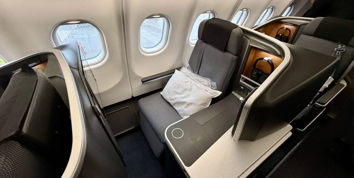 business class seat on a plane next to open windows