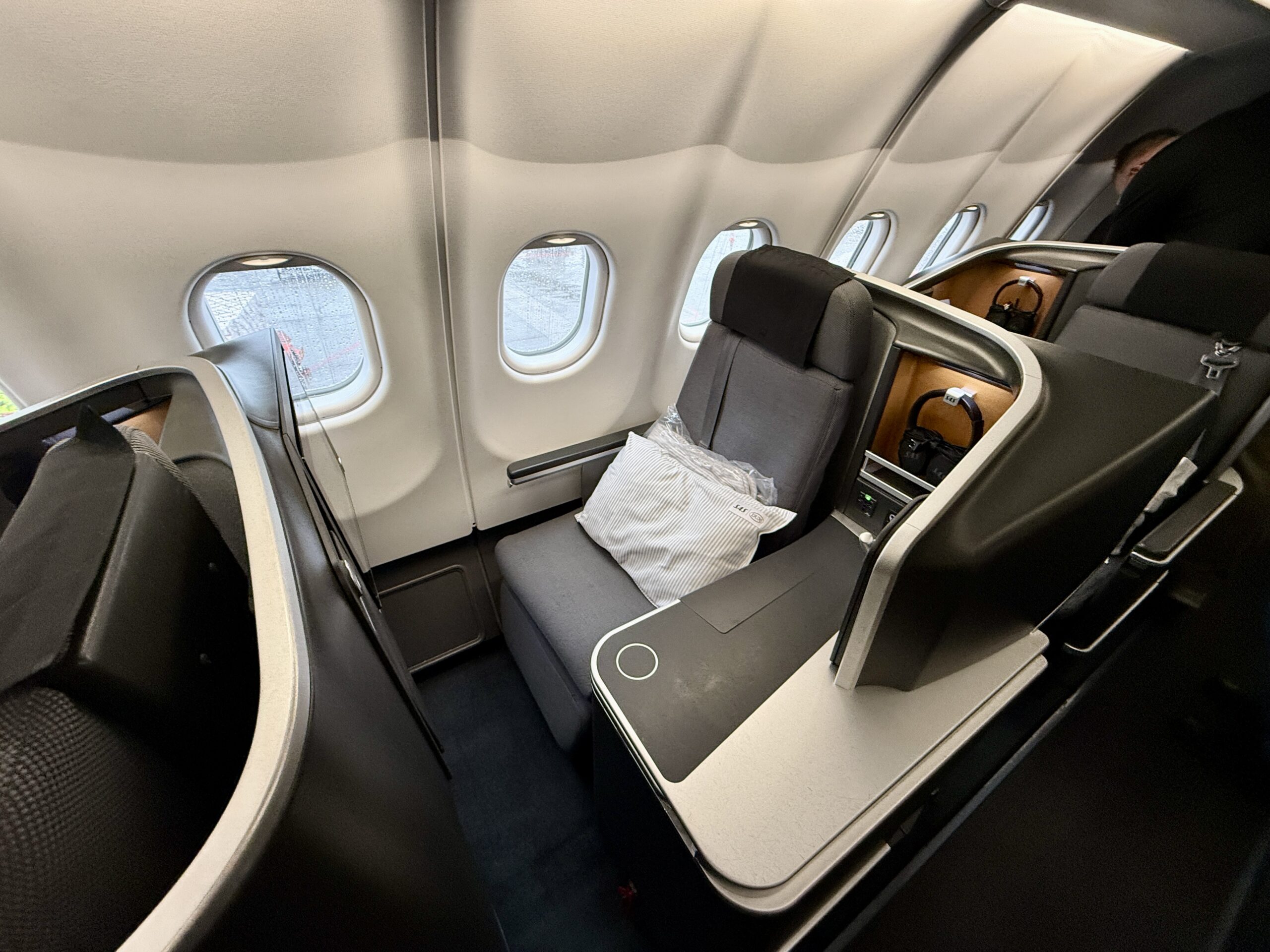 business class seat on a plane with a pillow on it