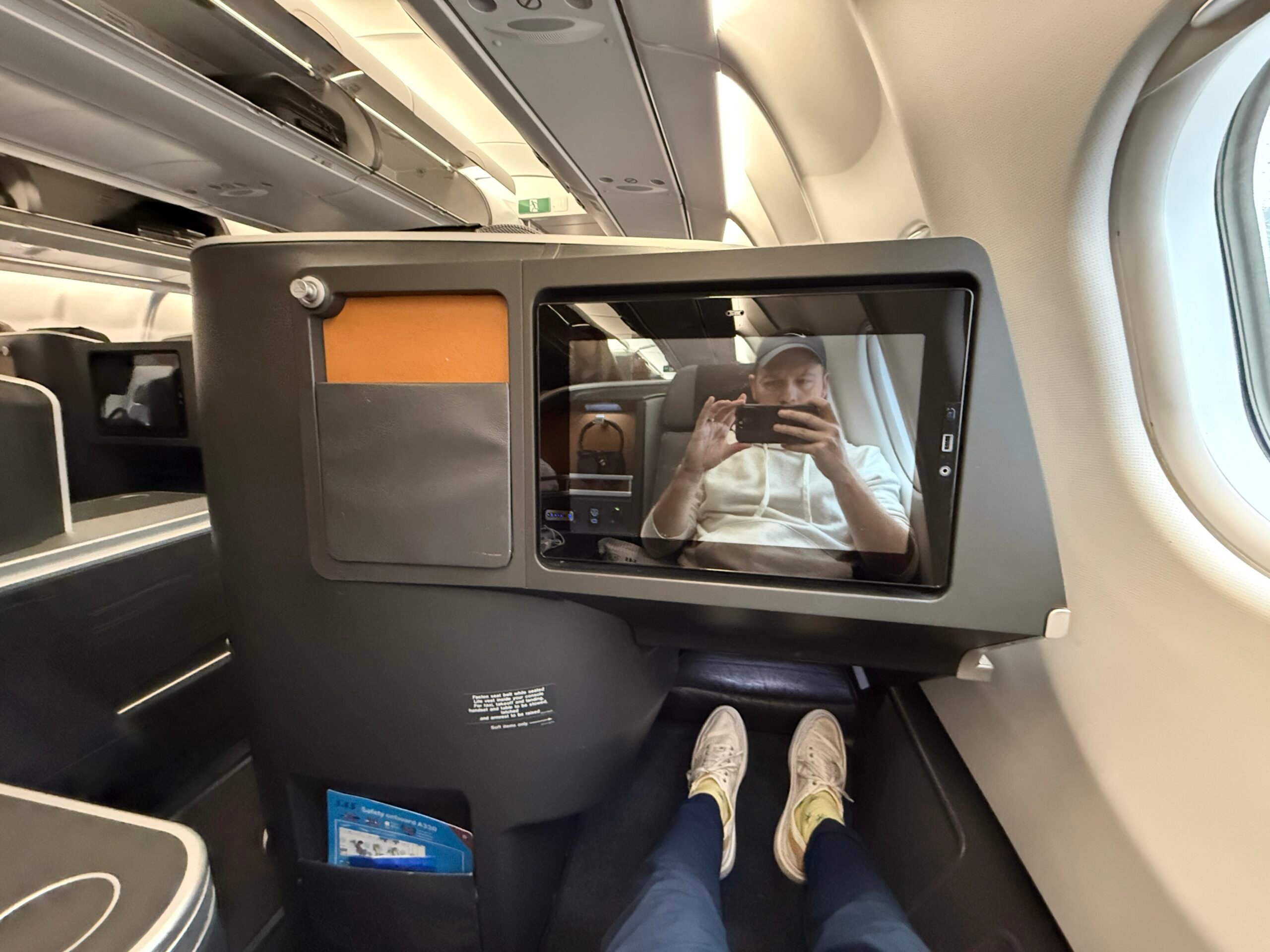 seatback screen on a plane with a man in the reflection