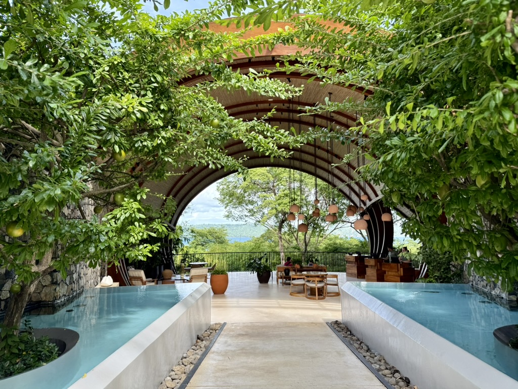 Entrance arch at the Andaz Peninsula Papagayo with vegetation and water on both sides of the walkway