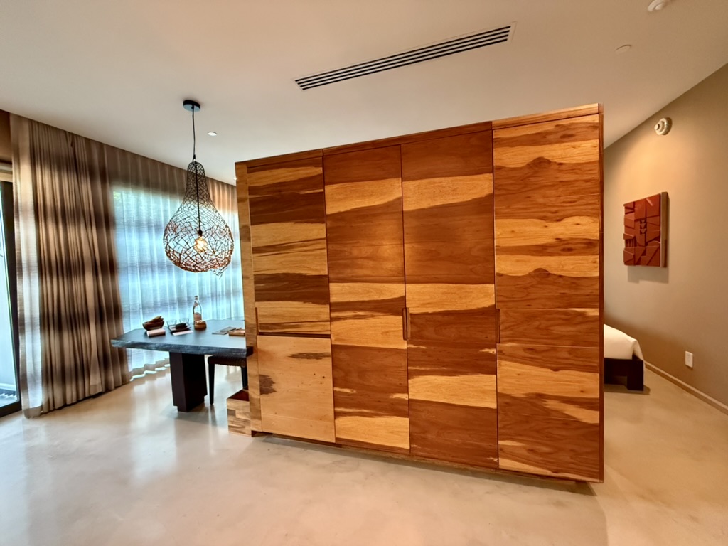 Large armoire and desk separating the bathroom and bedroom