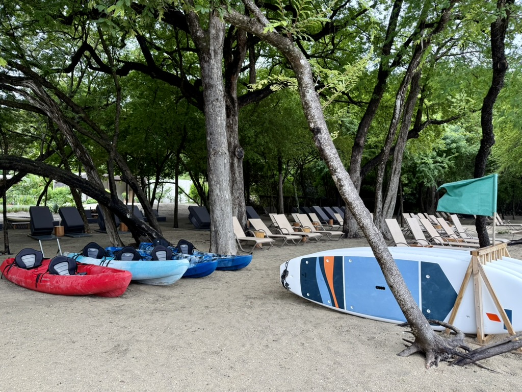 Paddle boards, kayaks, and lounge chairs on a beach