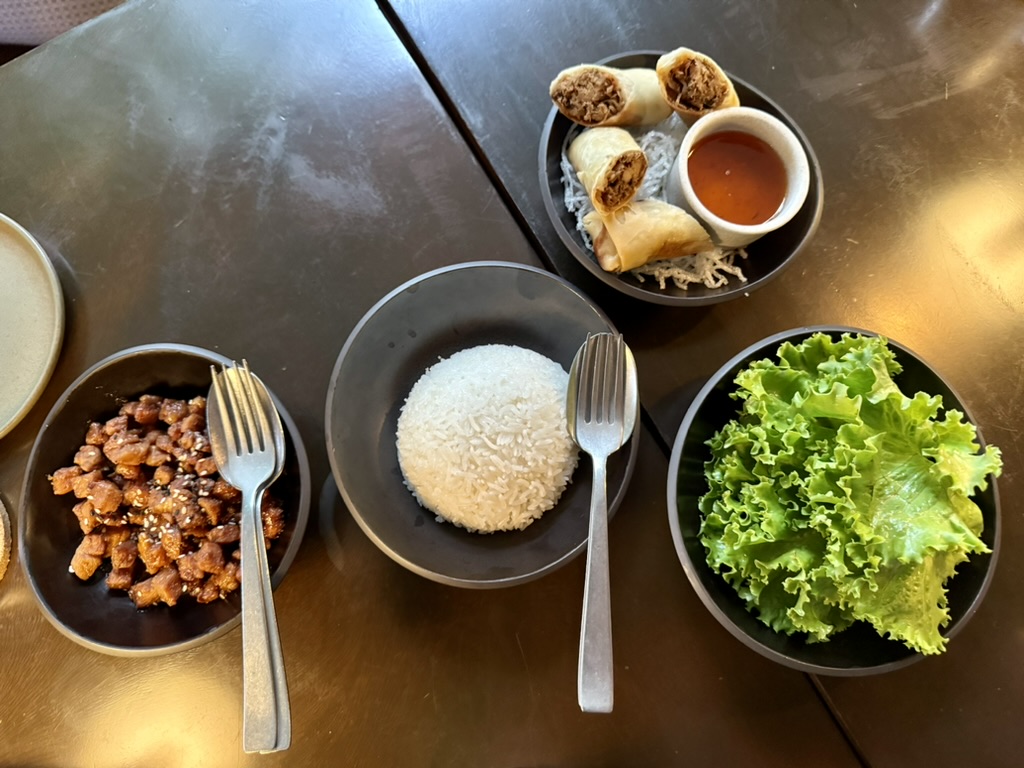 A bowl of spring rolls with pho, pork and adobo bites, and rice, with lettuce wraps at Ostra. 