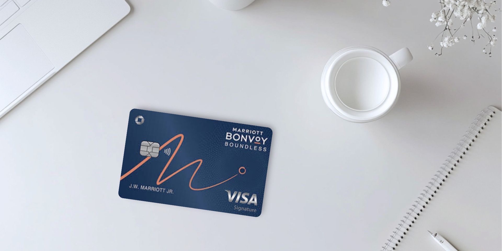 Marriott Bonvoy Boundless credit card with cup of coffee, floral arrangement, and laptop on a white desk.