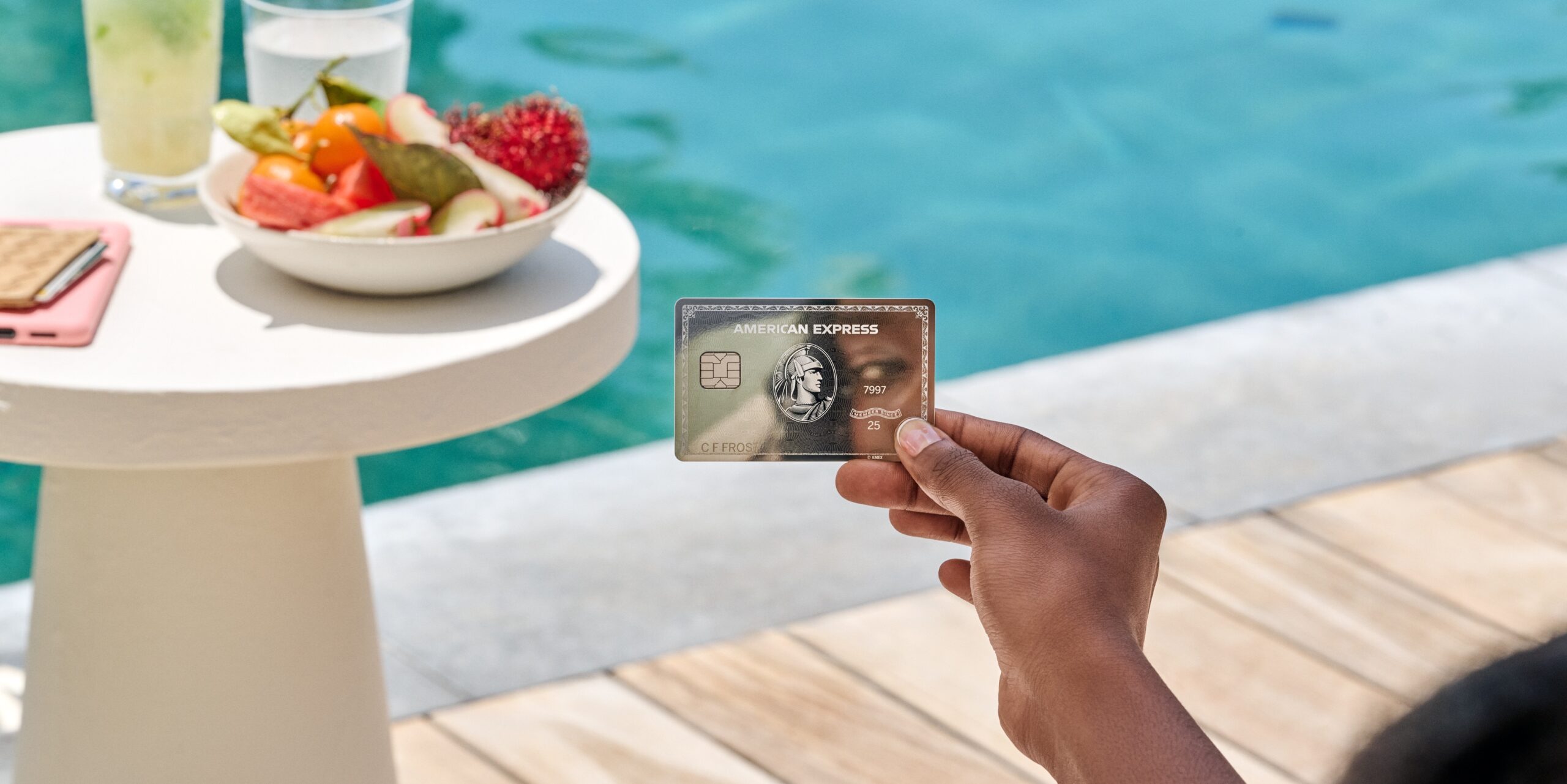 Hand holding amex platinum with pool in the background