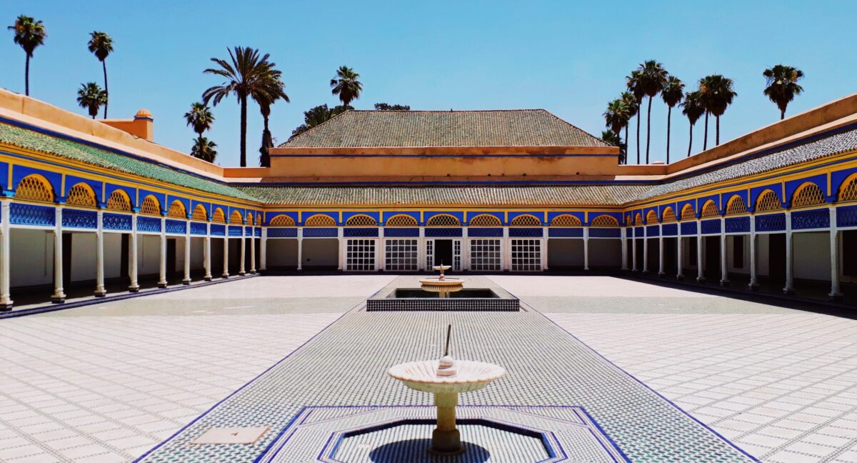 palace with blue tiles and gold finishes with palm trees in background