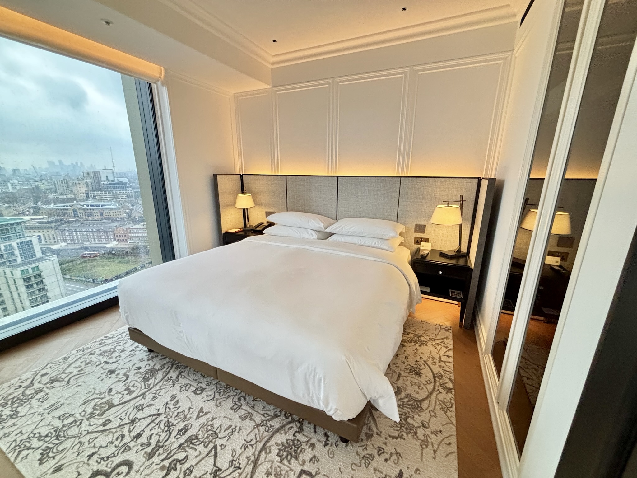 Inside the Park Hyatt London River Thames: Rooms, Dining, Pool & More 21 A king sized bed with floor-to-ceiling windows, a rug, and nightstands with lamps