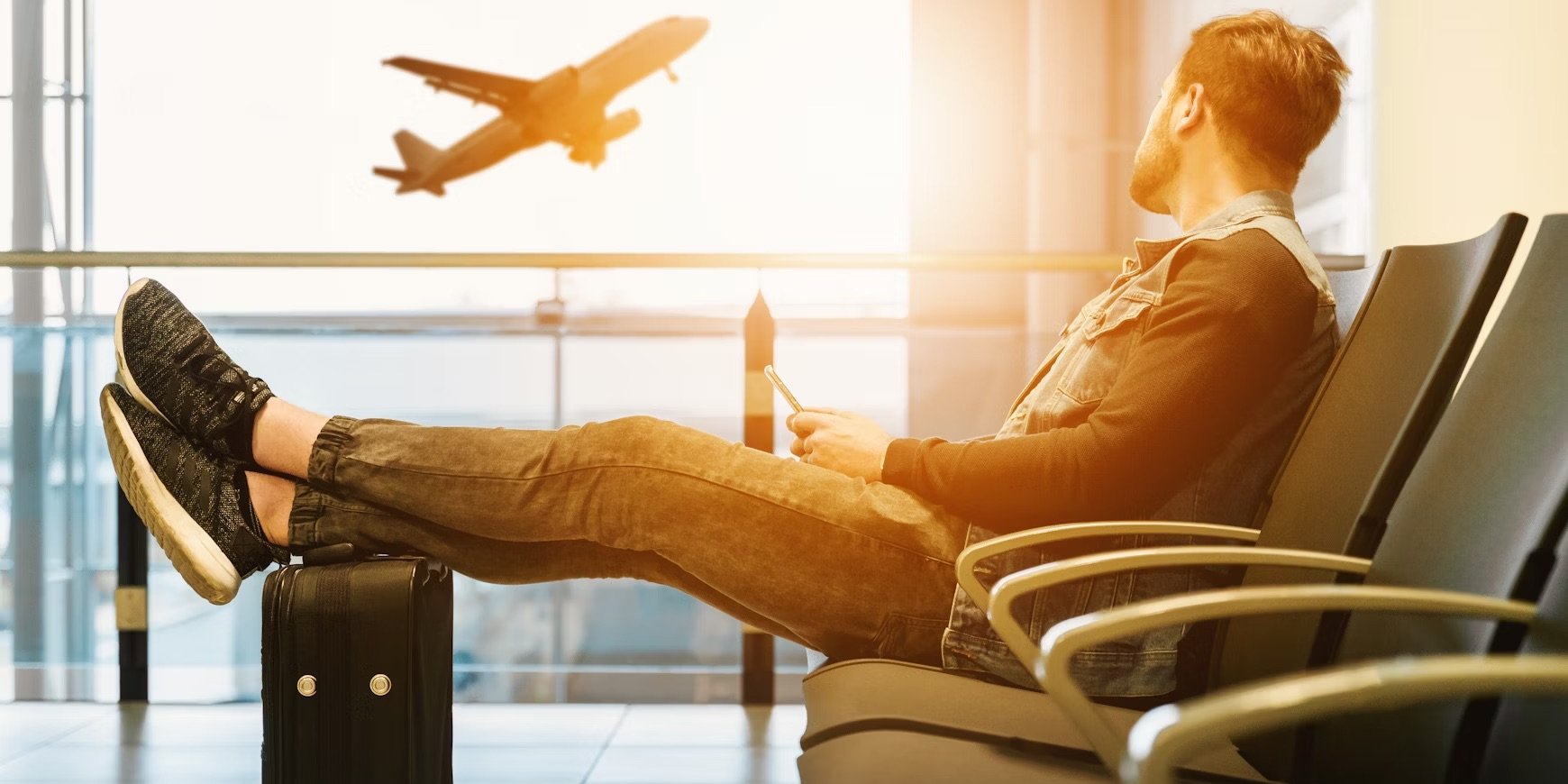 Tired Traveler With Feet Up on Bag as Airplane Takes Off in Background