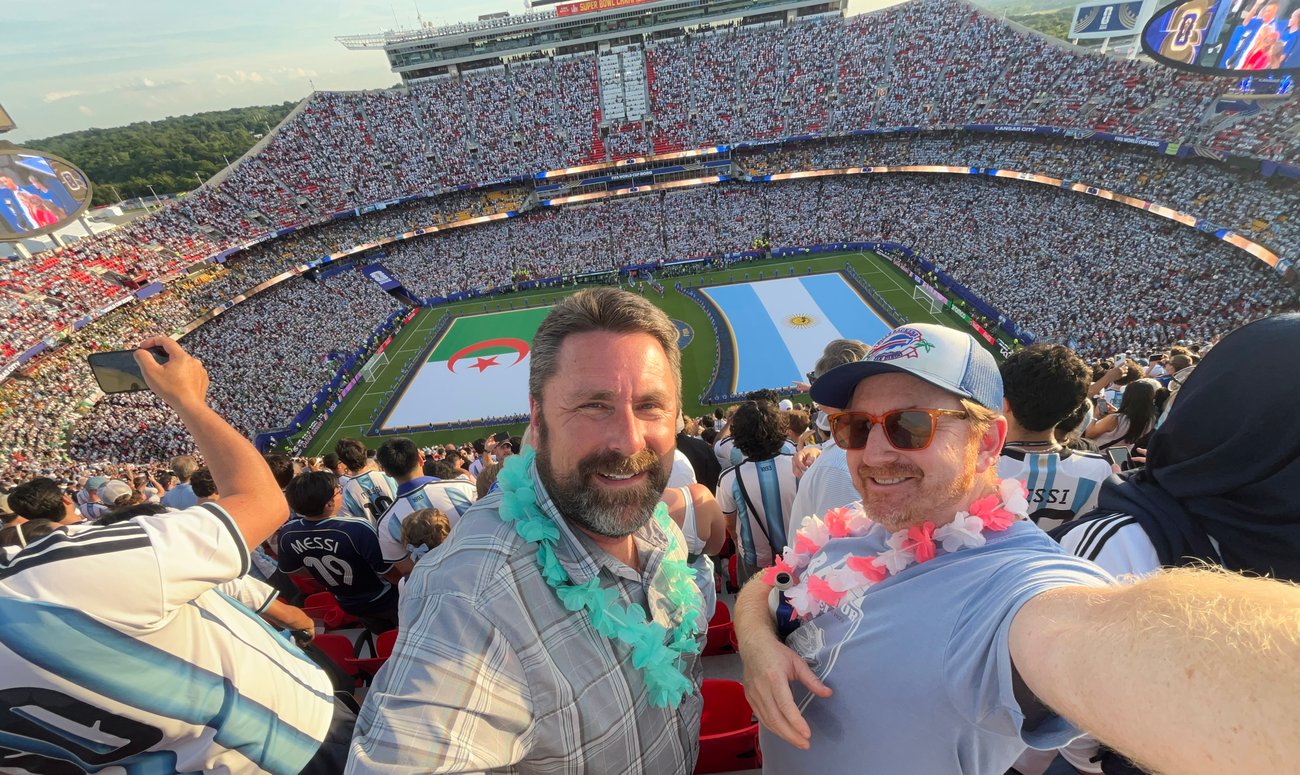 The Extra Mile, June 25: Delta's CEO Says High Fares Will Stay, World Cup Savings & More 3 two men in soccer stadium smiling