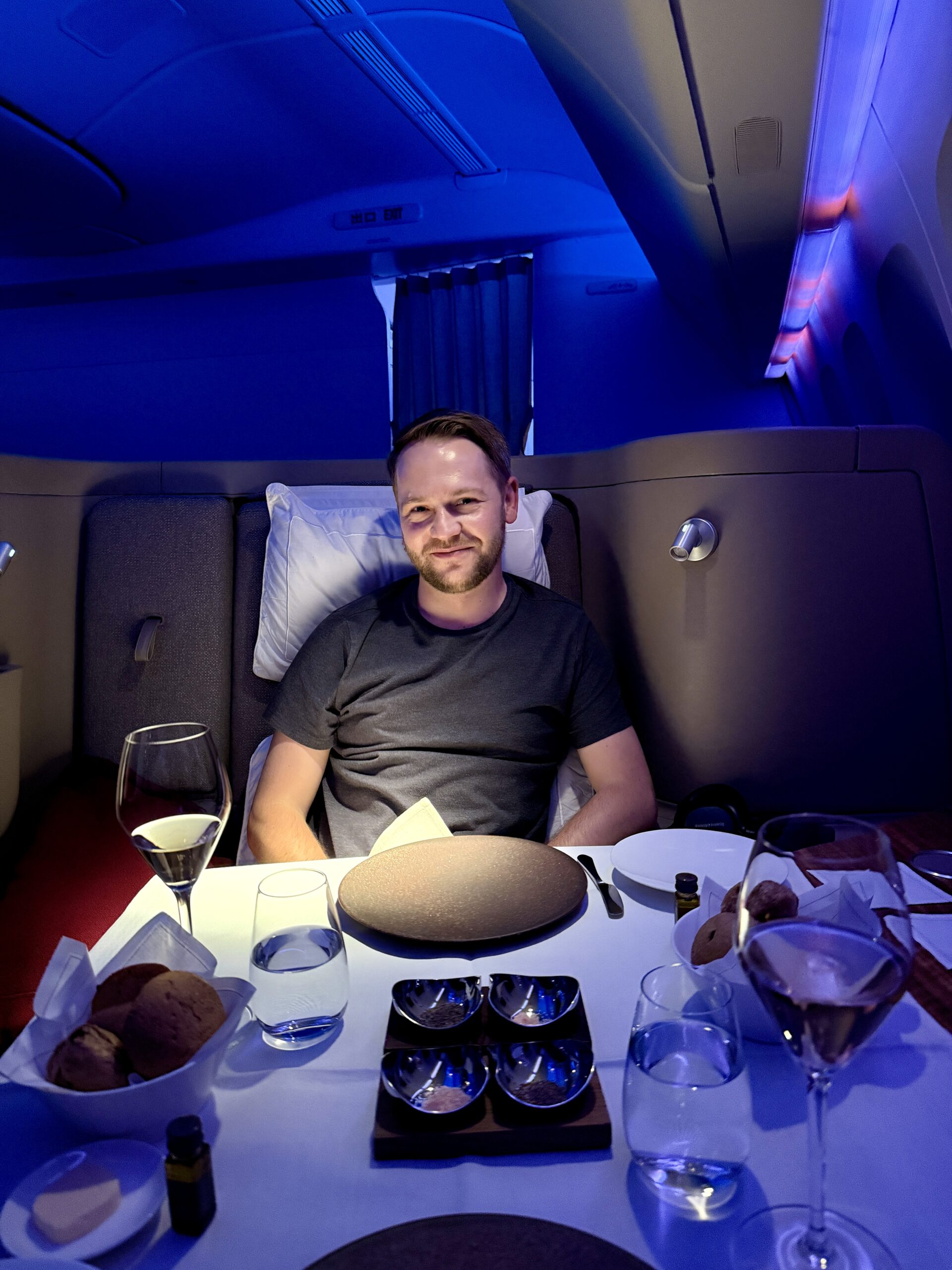 Aging Like a Fine Wine: Cathay Pacific First Class 777 Review 31 man sitting in airplane seat with table full of dishes